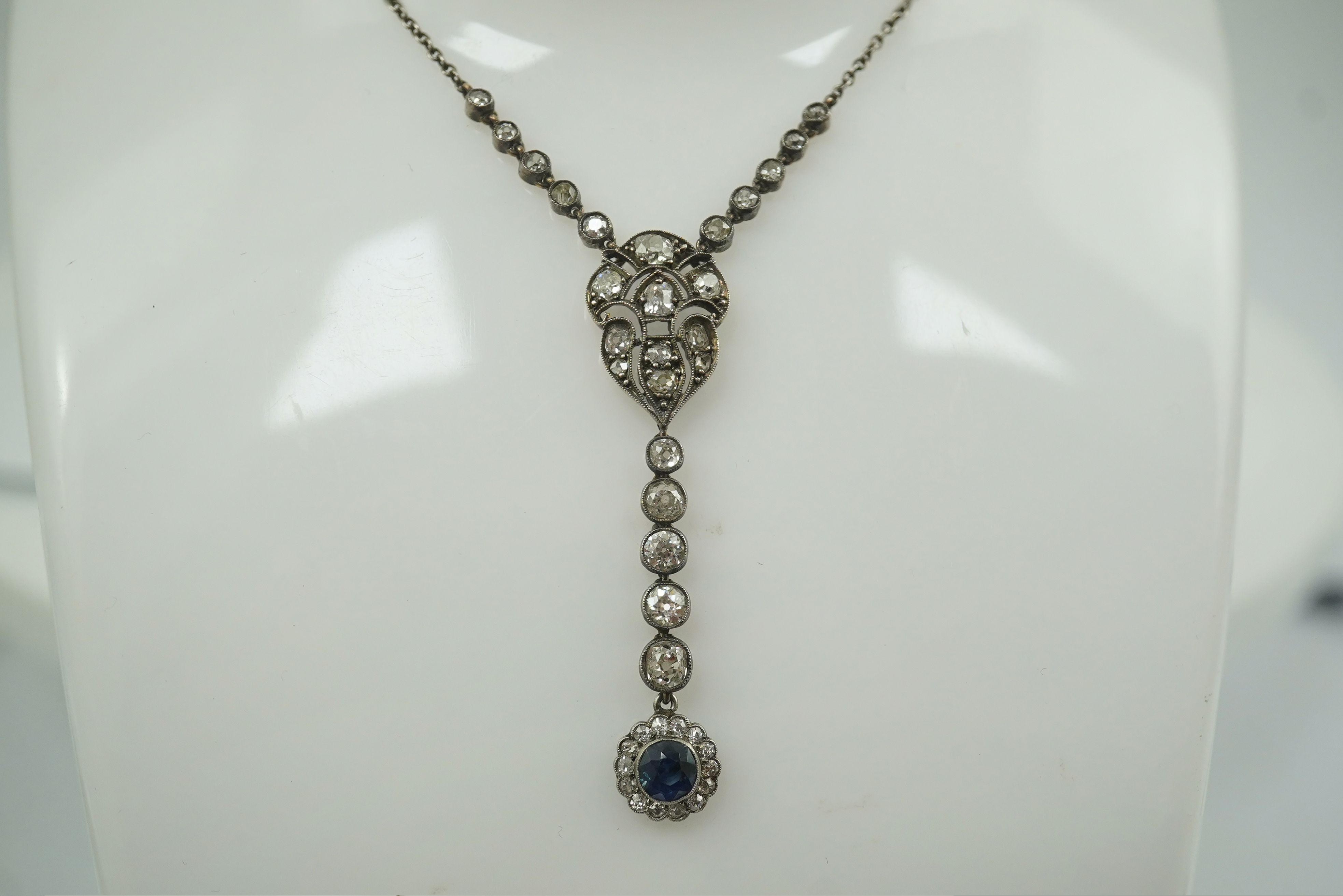 A Belle Epoque gold and silver, millegrain set sapphire and diamond cluster set drop pendant necklace